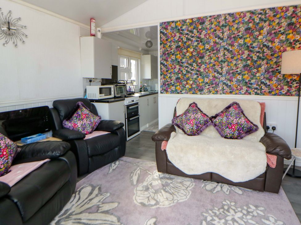 A living room with sofas and a kitchen area at The Comfort Den near Aberystwyth
