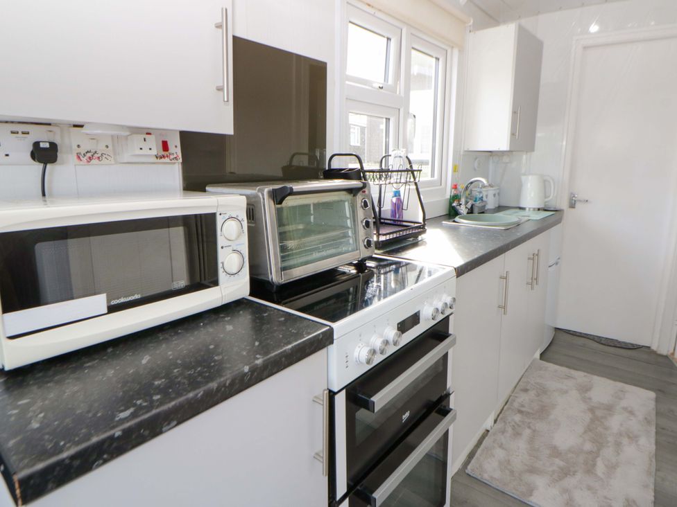 A kitchen with a microwave, oven, and sink at The Comfort Den near Aberystwyth