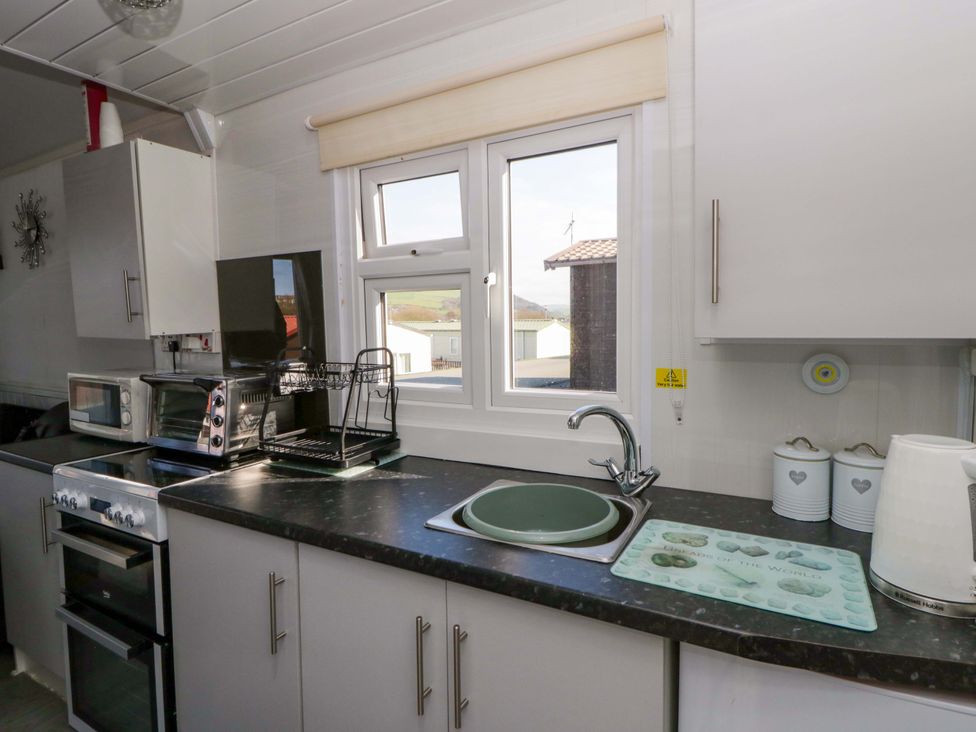 A kitchen with sink, cupboard, microwave and window at The Comfort Den near Aberystwyth