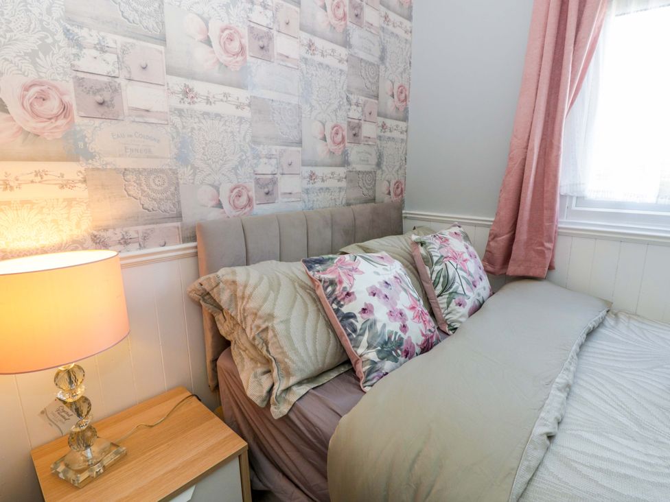 A bedroom with a bed, pillows, and a lamp at The Comfort Den near Aberystwyth