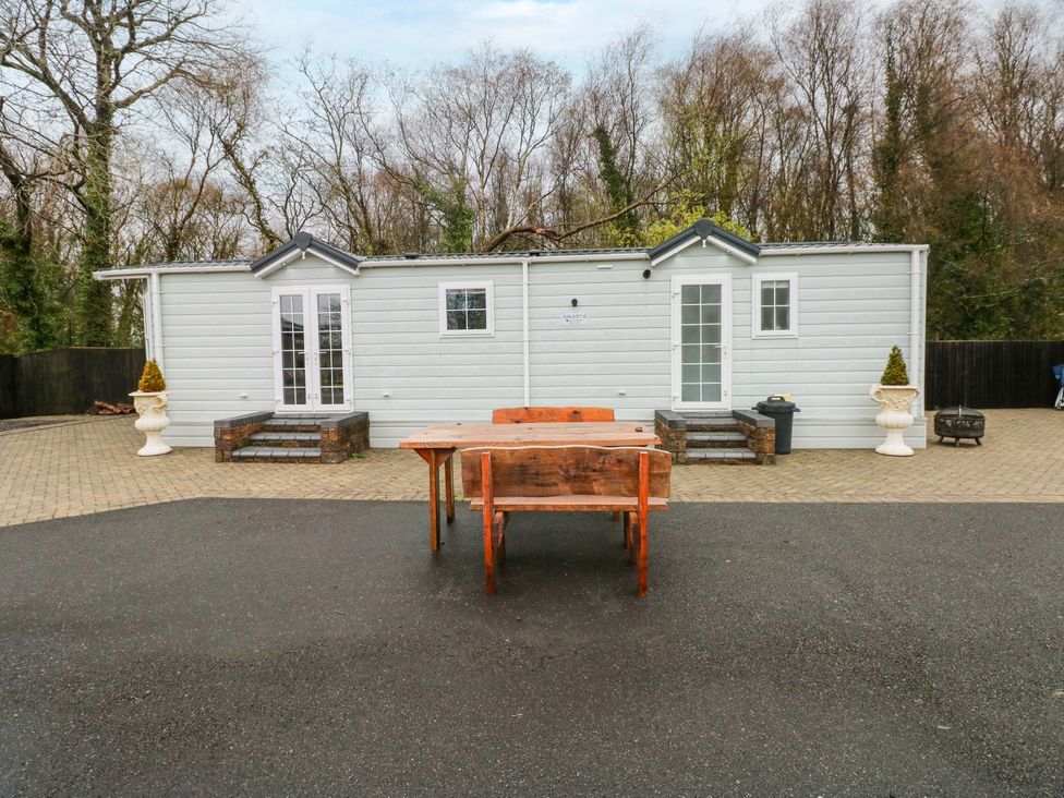 An outdoor area with two buildings and a table at Meadows Farm Lodge in Gorseinon