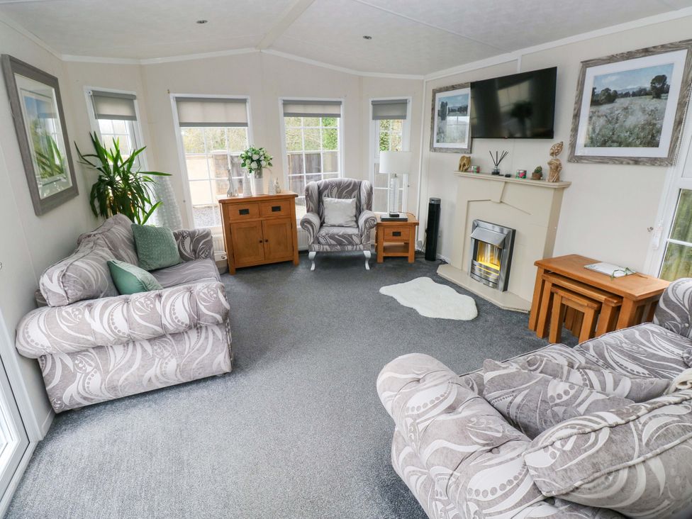 A living room with a sofa and a TV at Meadows Farm Lodge in Gorseinon