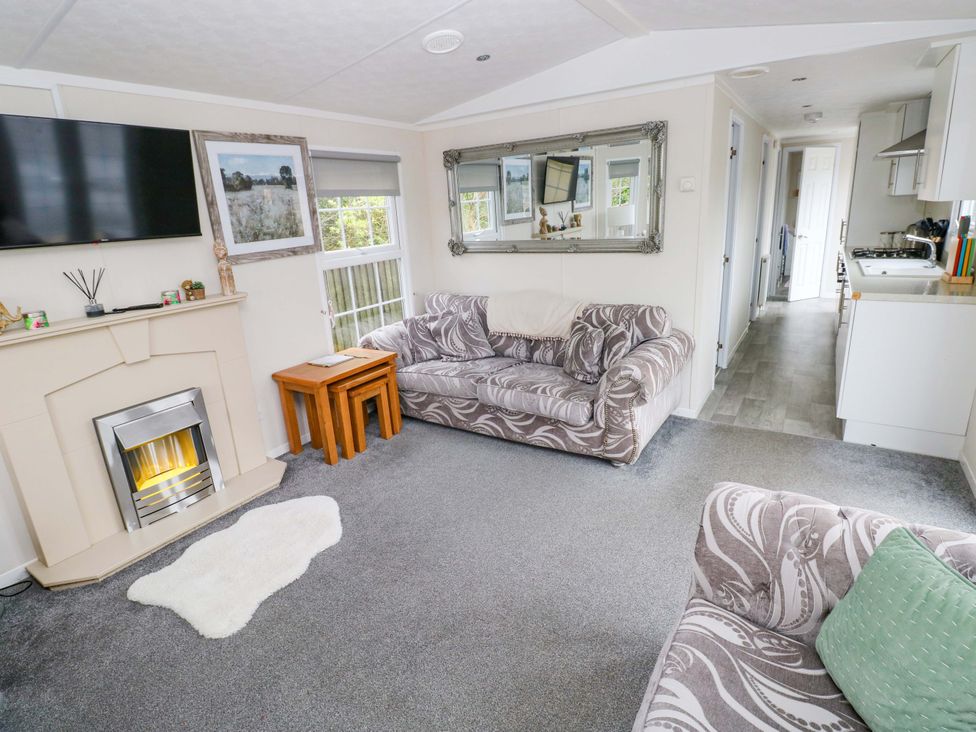A living room with a sofa and television at Meadows Farm Lodge in Gorseinon