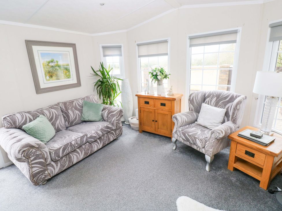 A snug with a sofa and armchair at Meadows Farm Lodge in Gorseinon