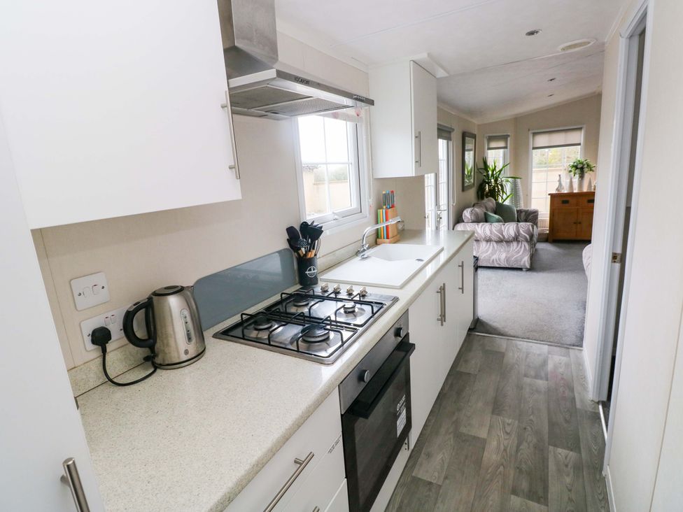 A kitchen with a stove, sink, and kettle at Meadows Farm Lodge in Gorseinon