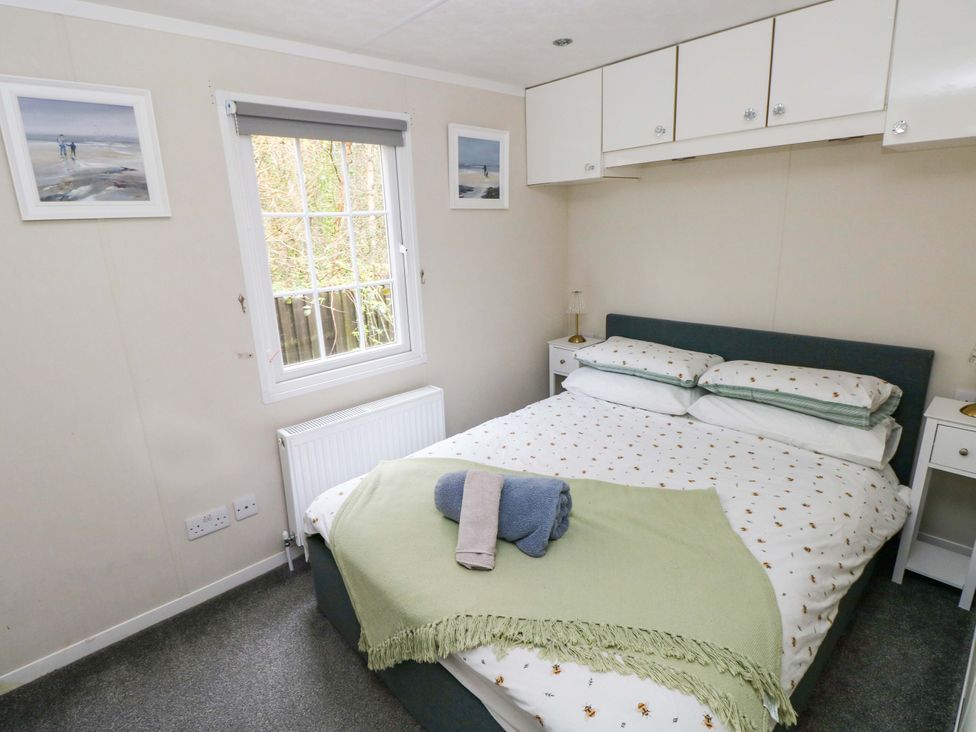 A bedroom with a bed and nightstand at Meadows Farm Lodge in Gorseinon