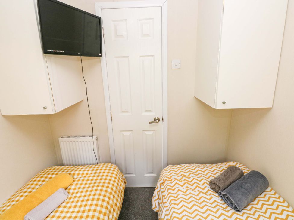 A bedroom with two beds and a television at Meadows Farm Lodge in Gorseinon