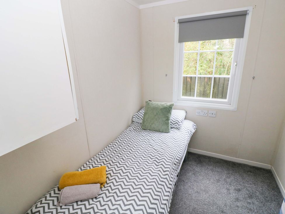 A bedroom with a bed and towels at Meadows Farm Lodge in Gorseinon
