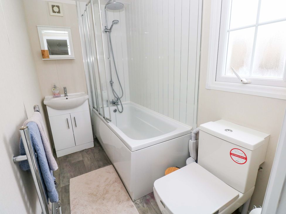 A bathroom with a bathtub, shower, toilet, and sink at Meadows Farm Lodge in Gorseinon