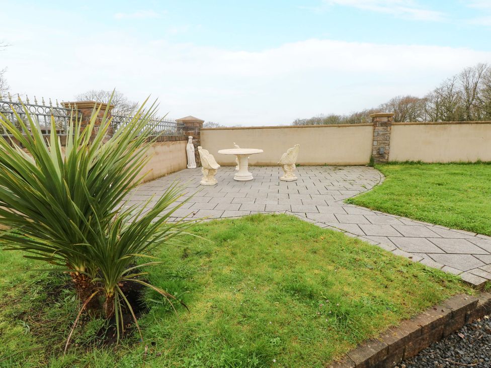 A garden with a table and statues at Meadows Farm Lodge in Gorseinon