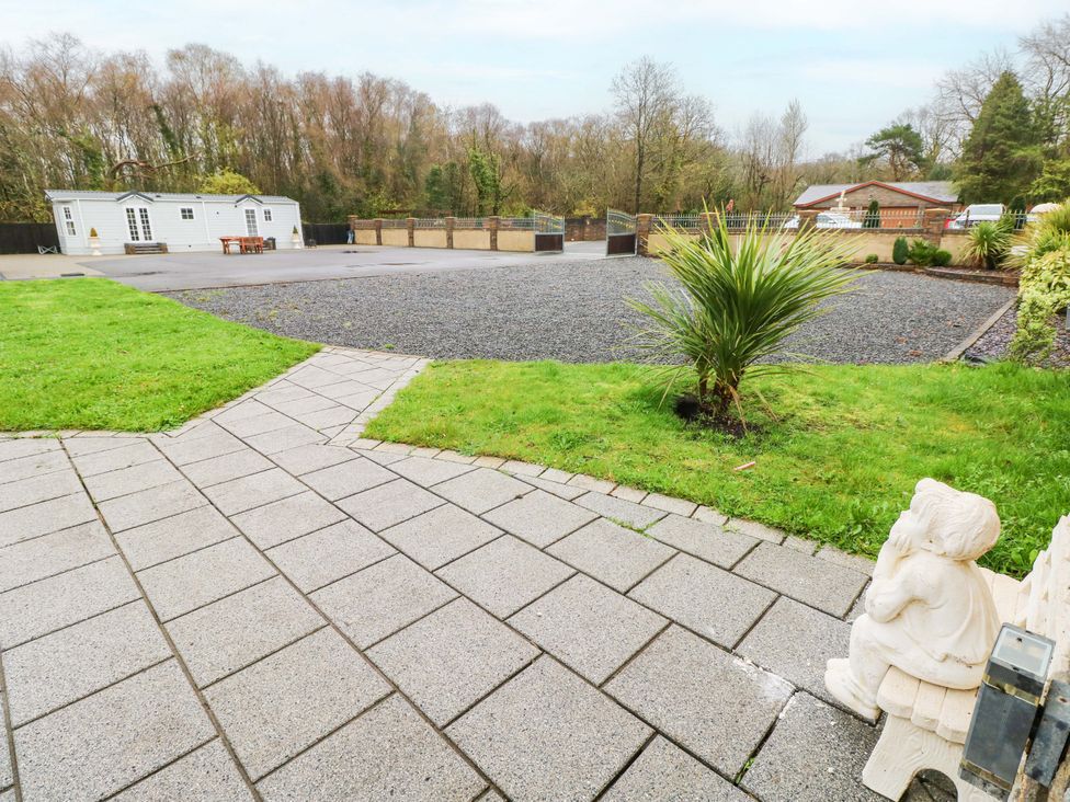 A garden with a pathway, gravel area, and a caravan at Meadows Farm Lodge in Gorseinon