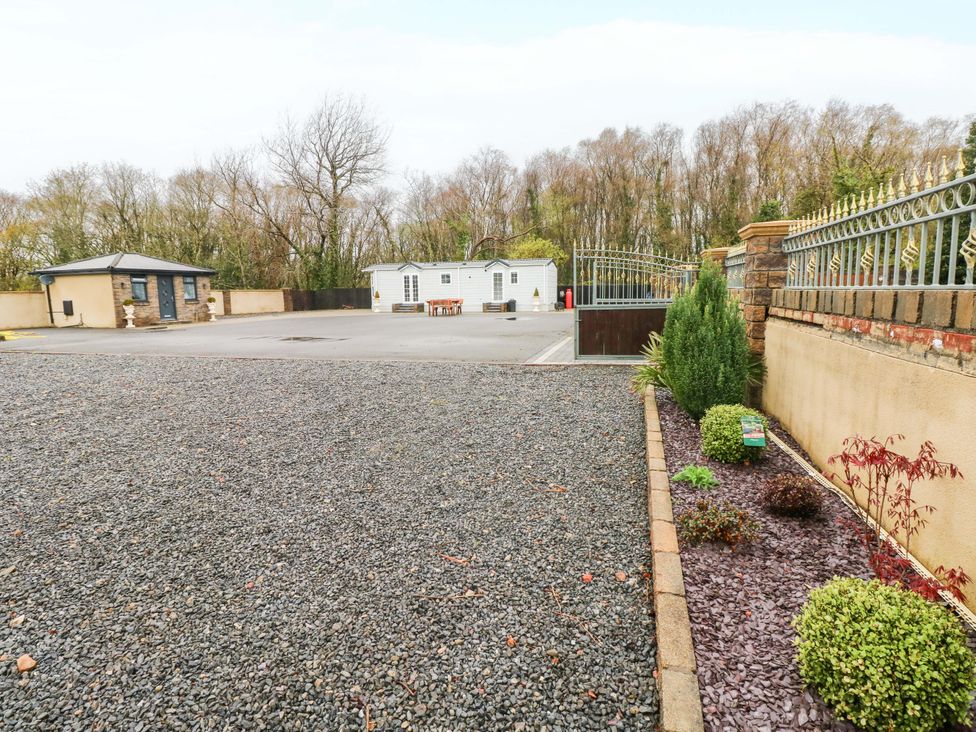 An outdoor area with gravel, plants, and buildings at Meadows Farm Lodge in Gorseinon