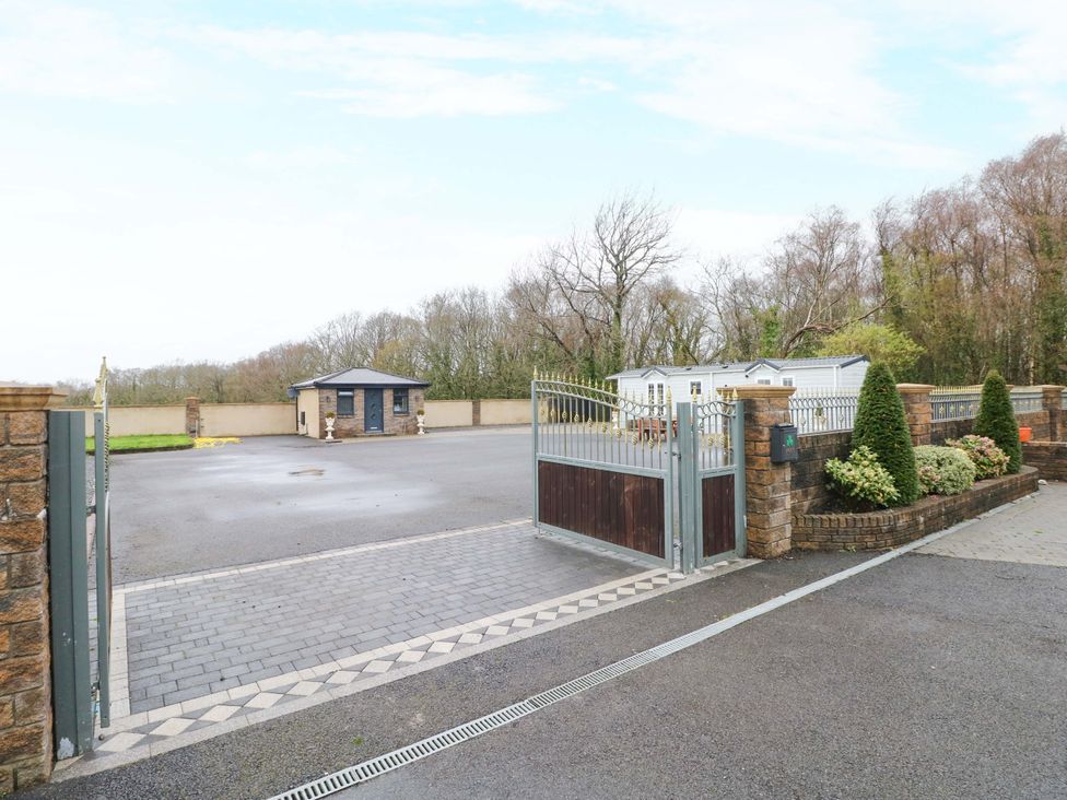 An entrance with a gate and guard house at Meadows Farm Lodge in Gorseinon
