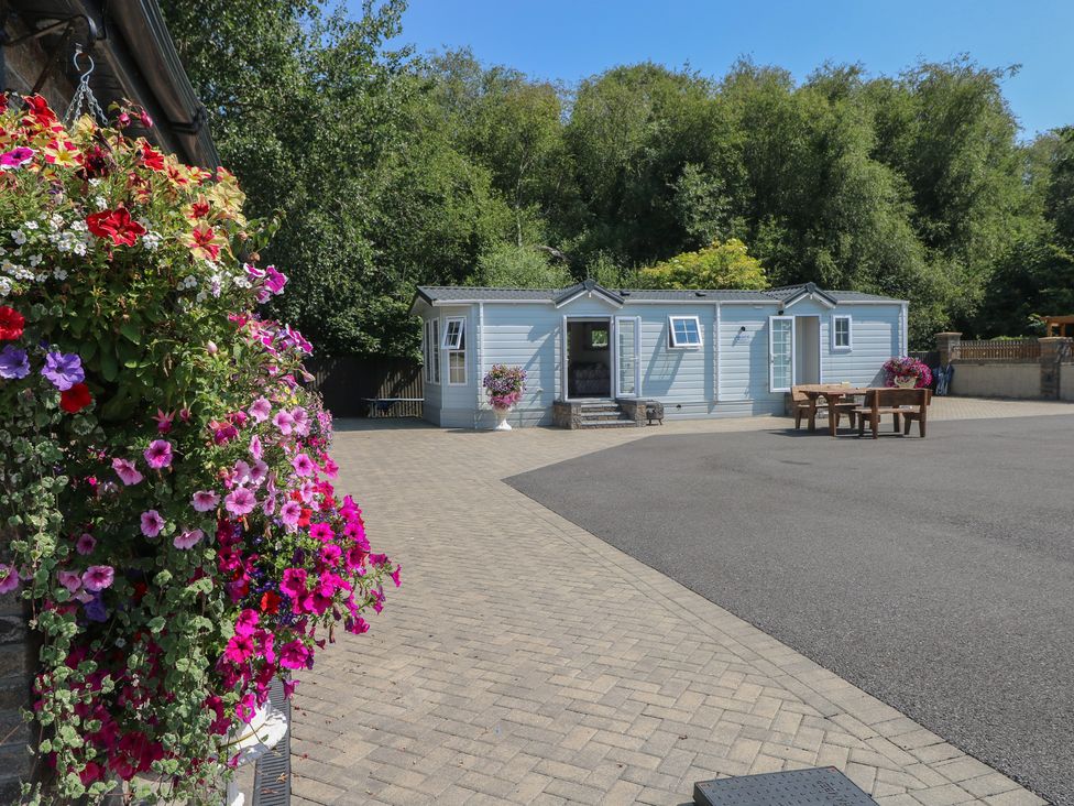 An outdoor area featuring a lodge and table at Meadows Farm Lodge in Gorseinon