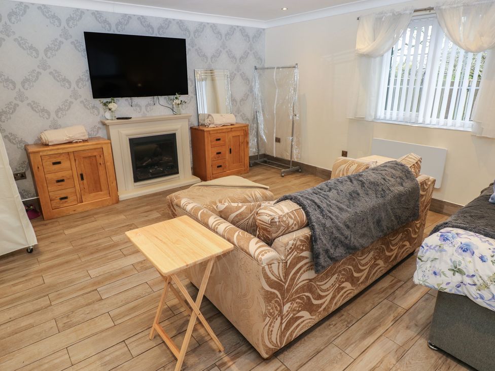 A living room with a sofa and television at Annexe @ Meadows Farm Swansea