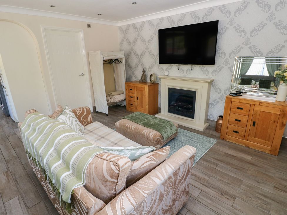 A living room with a sofa and television at Annexe @ Meadows Farm in Gorseinon