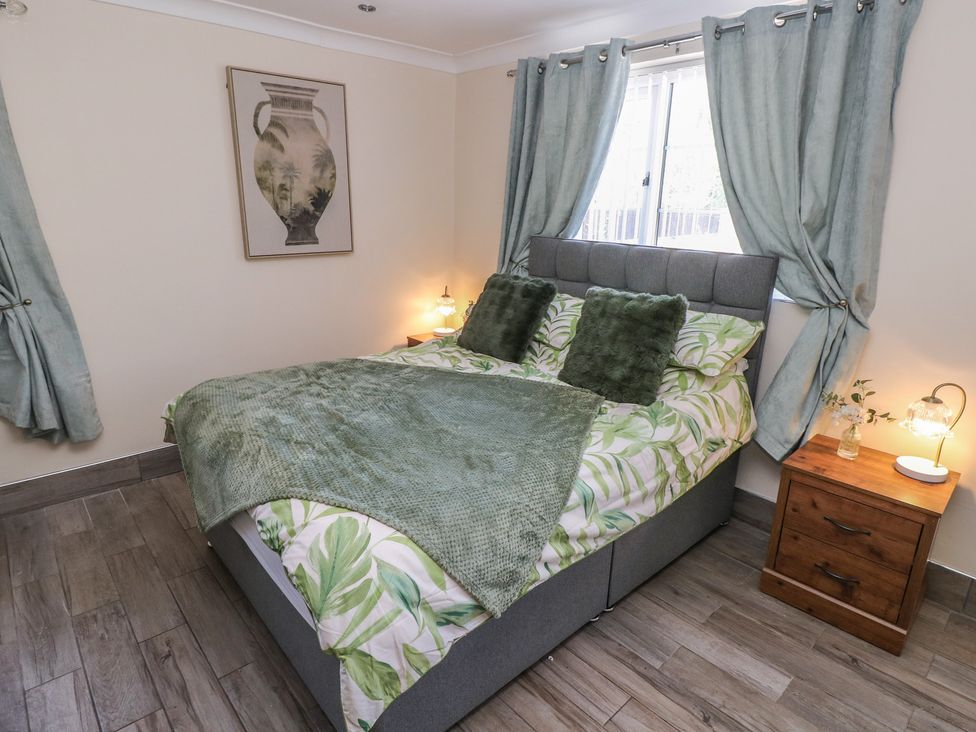 A bedroom with a bed and bedside table at Annexe @ Meadows Farm in Gorseinon