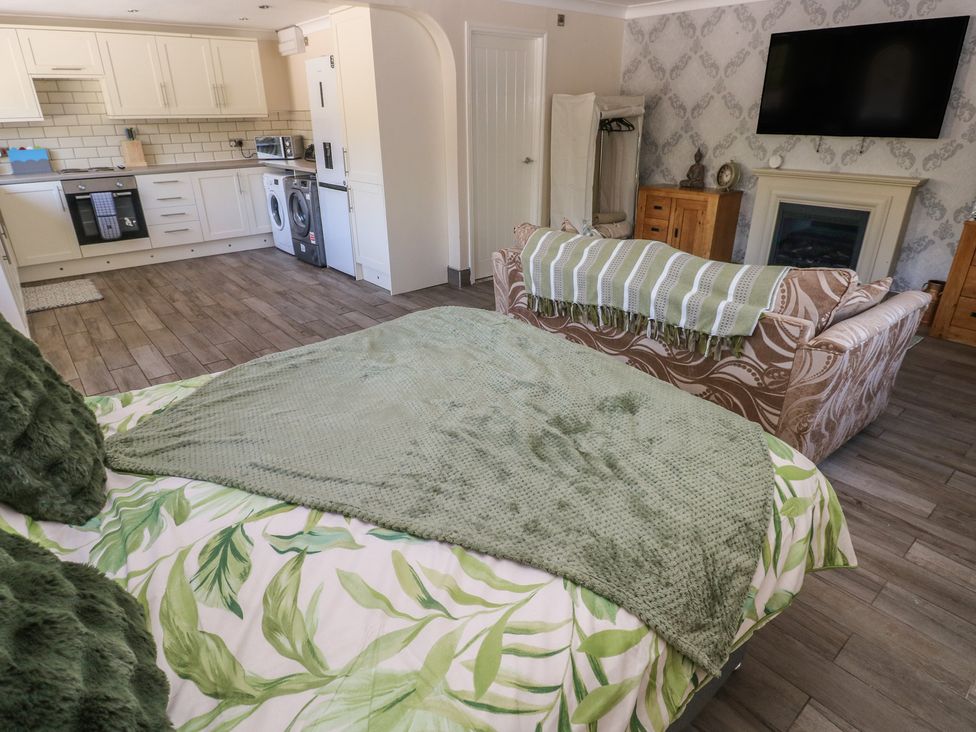 A living room with a kitchen area and a bed at Annexe @ Meadows Farm in Gorseinon