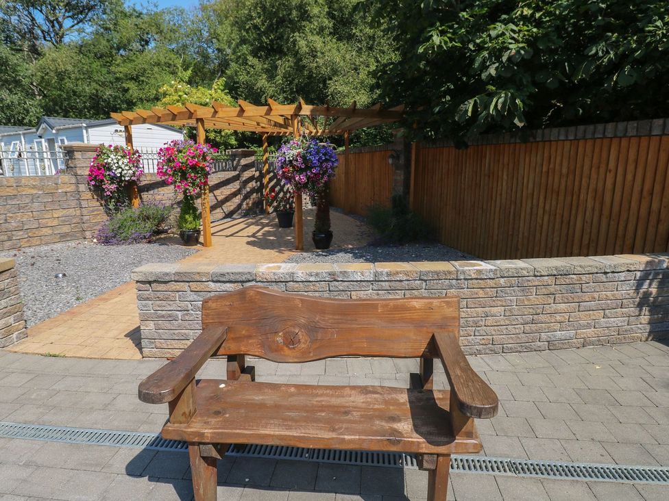 A garden with a wooden bench and flower pots at Annexe @ Meadows Farm in Gorseinon