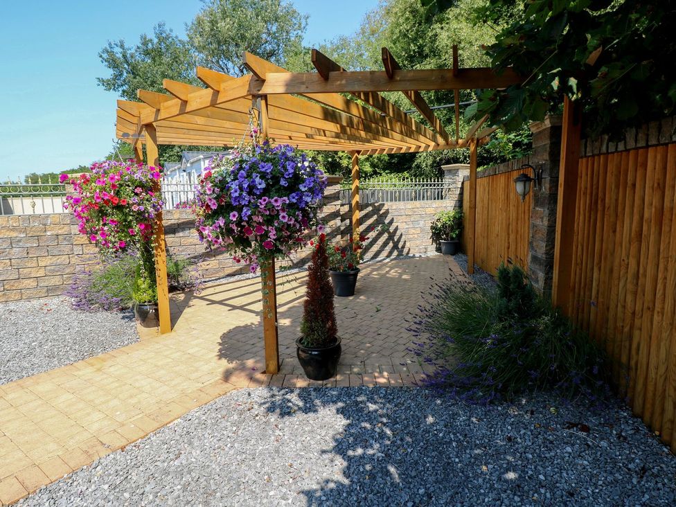 A garden with a pergola and flower pots at Annexe @ Meadows Farm in Gorseinon