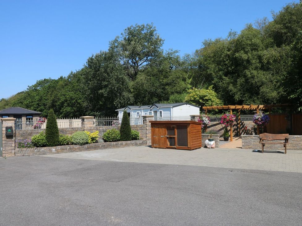 An outdoor area with a caravan and a bench at Annexe @ Meadows Farm, Gorseinon