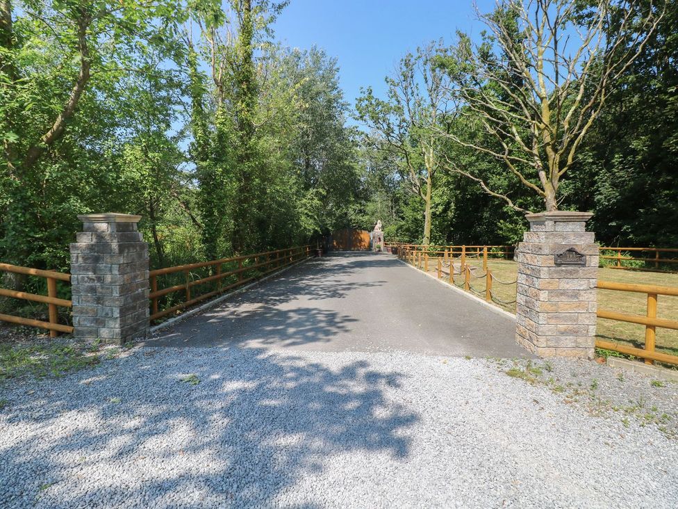 A gravel road with stone pillars and trees at Annexe @ Meadows Farm in Gorseinon