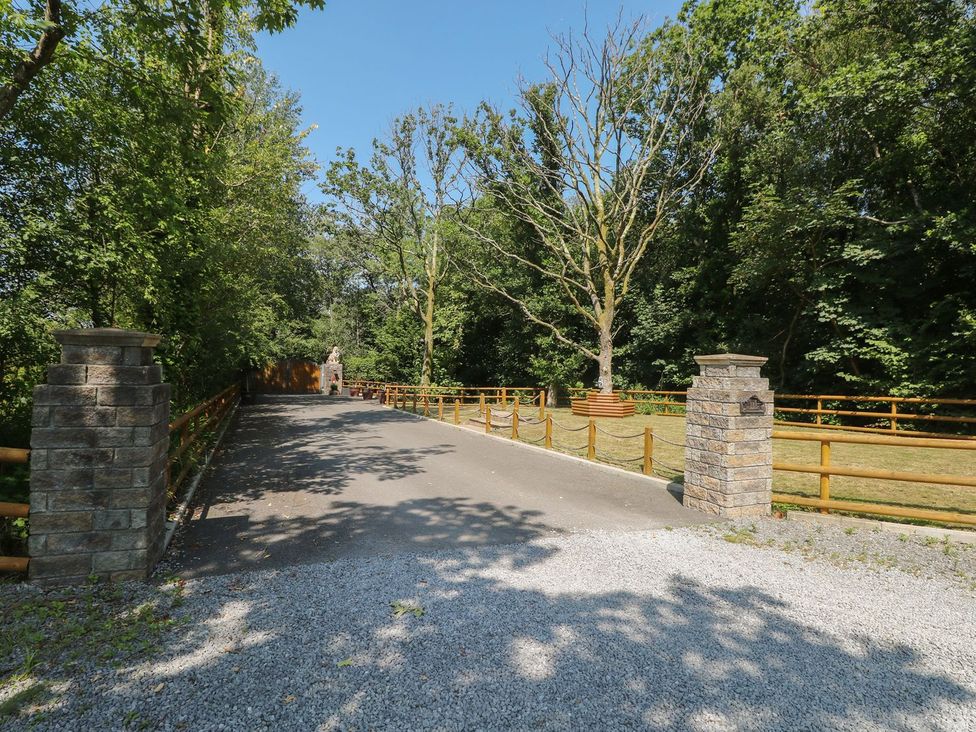 A gravel path lined with trees and stone pillars at Annexe @ Meadows Farm in Gorseinon