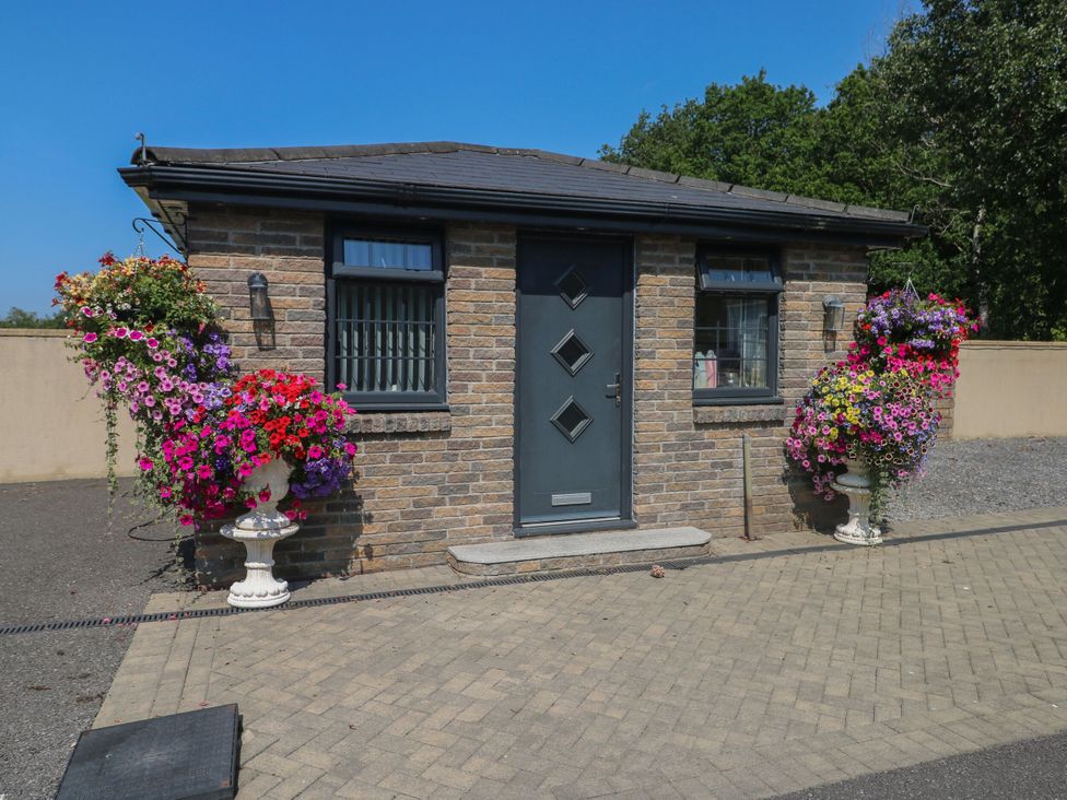 A brick building with a front door and flower pots at Annexe @ Meadows Farm, Gorseinon