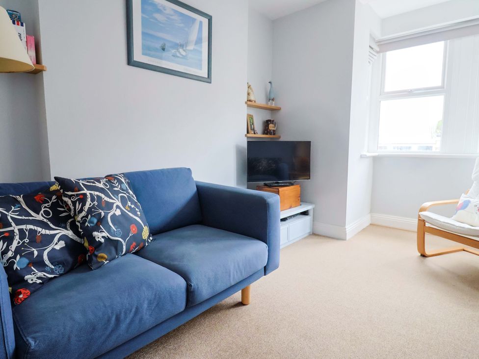 A living room with a blue sofa and television at 4 Peaslands Road Sidmouth