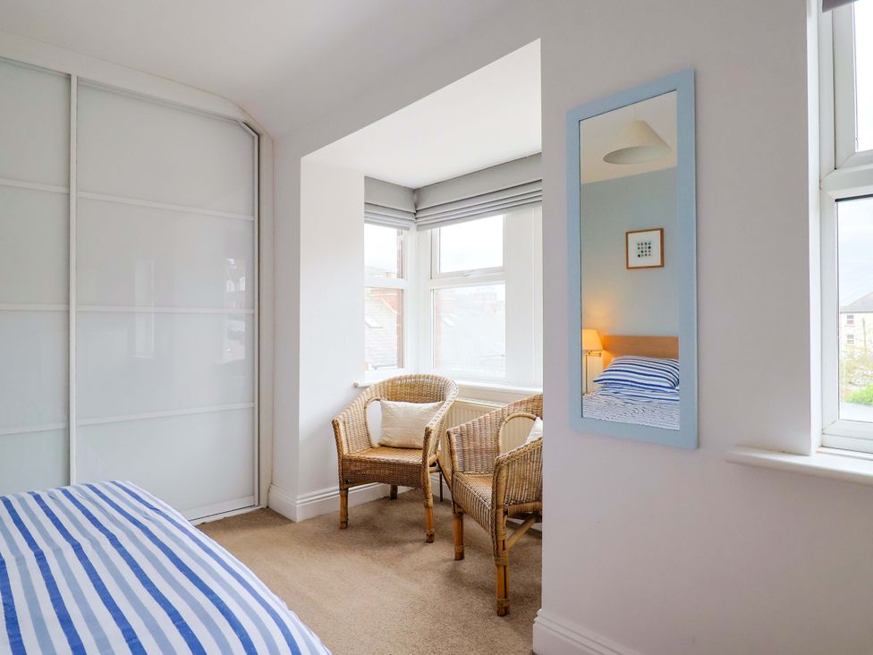 A bedroom with a bed and chairs near windows at 4 Peaslands Road Sidmouth
