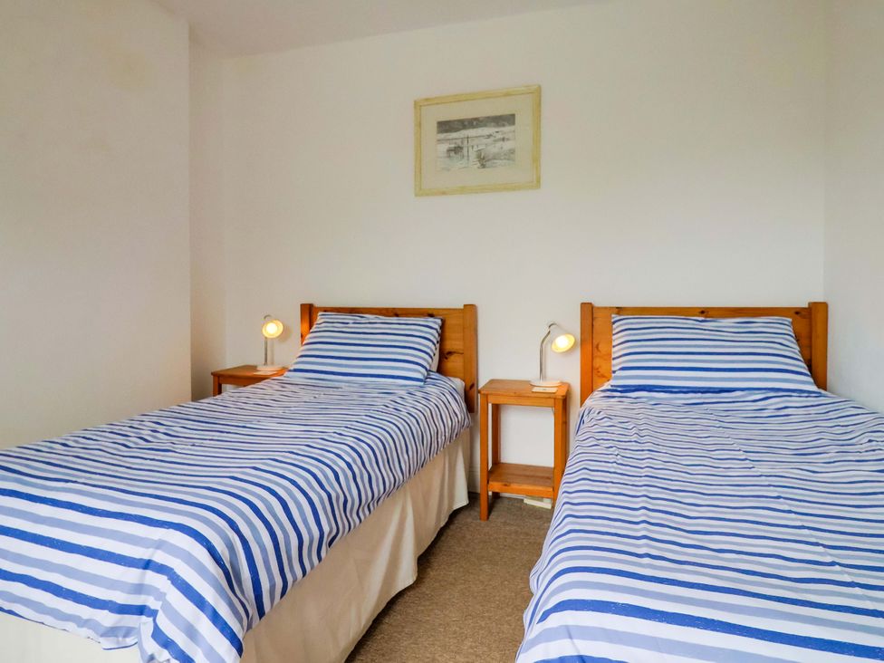 A bedroom with two beds and side tables at 4 Peaslands Road in Sidmouth