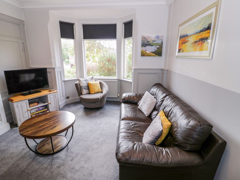 A living room with a sofa, coffee table, armchair, and television at 141 Barnards Green Road Barnard's Green, Malvern