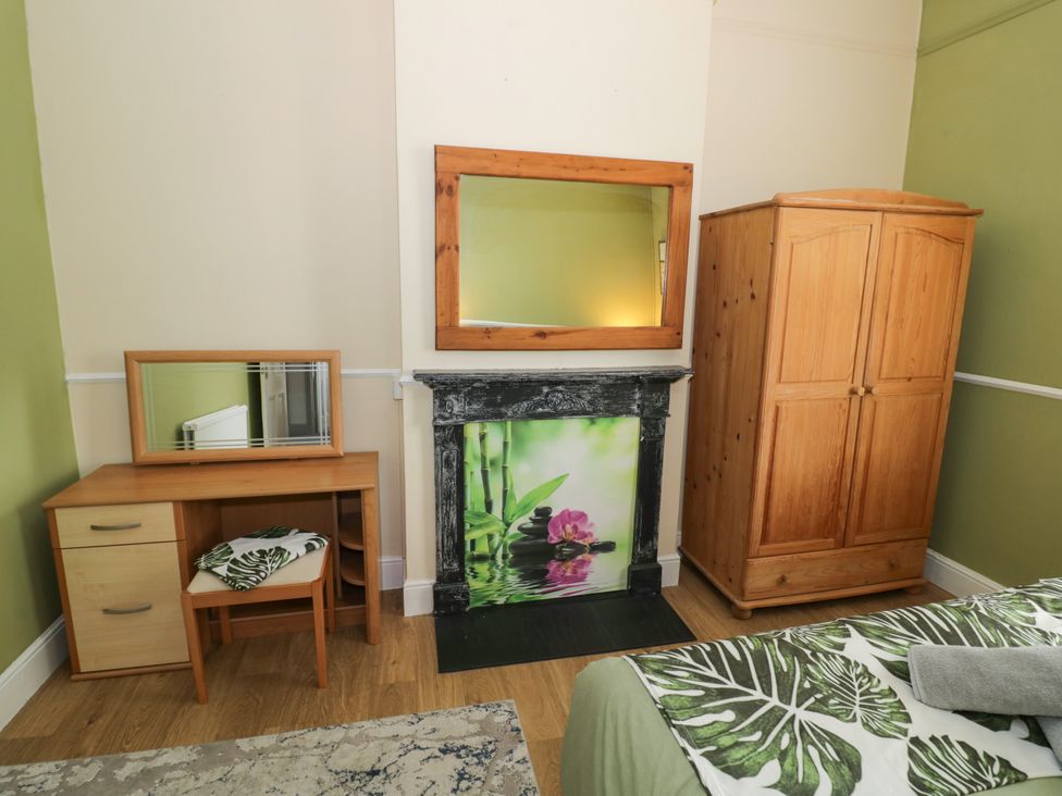 A bedroom with a mirror, wardrobe, and fireplace at 141 Barnards Green Road, Barnard's Green, Malvern