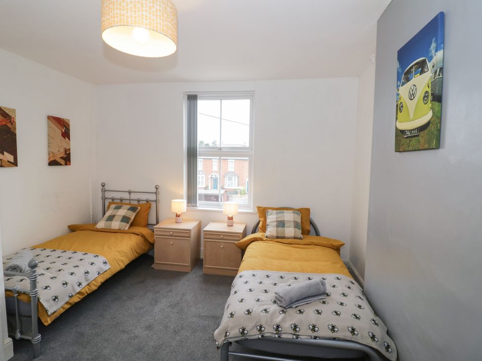 A bedroom with two beds, side tables, and artwork at 141 Barnards Green Road in Barnard's Green, Malvern