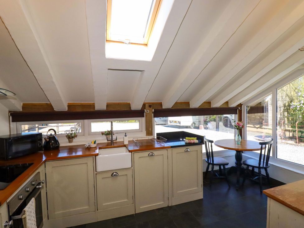A kitchen with a sink, stove, and dining table at Millies Place St Austell