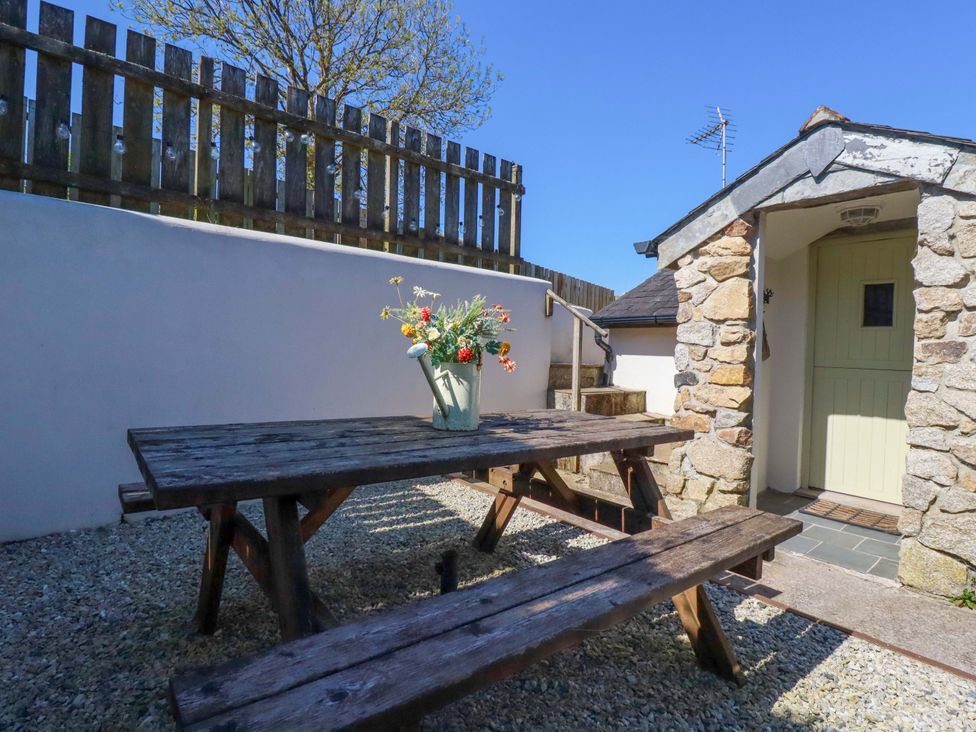 An outdoor seating area with a picnic table and flower vase at Millies Place St Austell