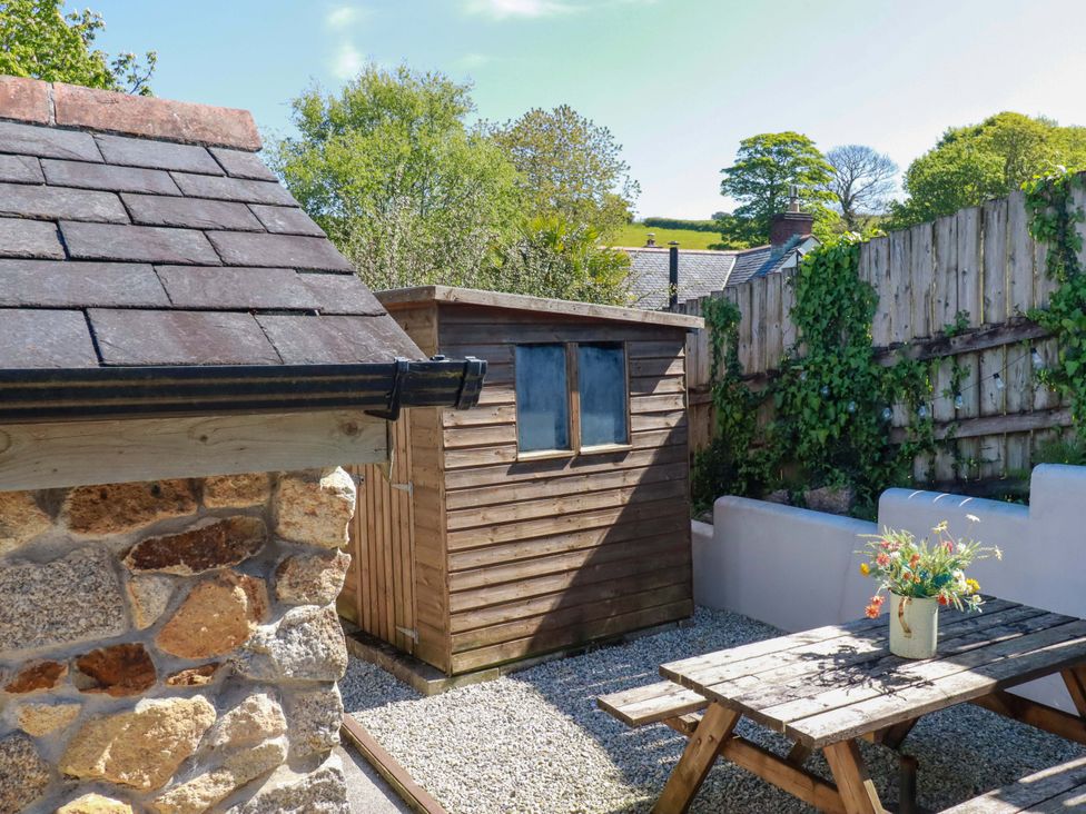 An outdoor area with a wooden shed and a table at Millies Place St Austell
