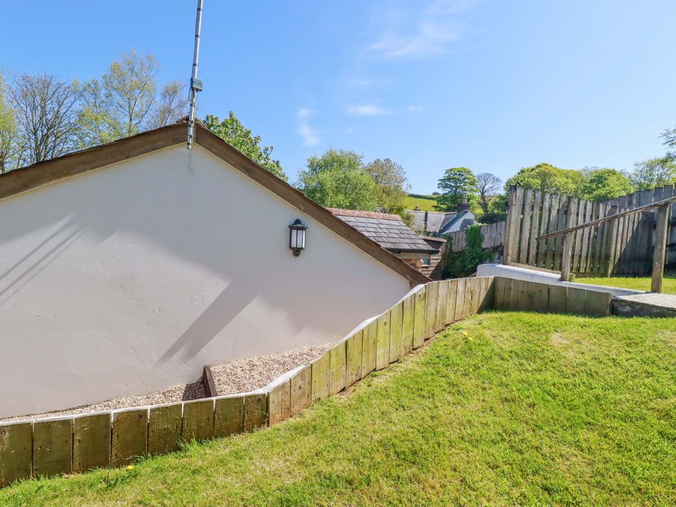 A view of a sloped garden with a wooden fence at Millies Place St Austell