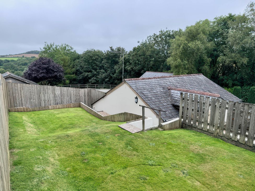 A garden with grass and a house in the background at Millies Place in Coombe near Grampound