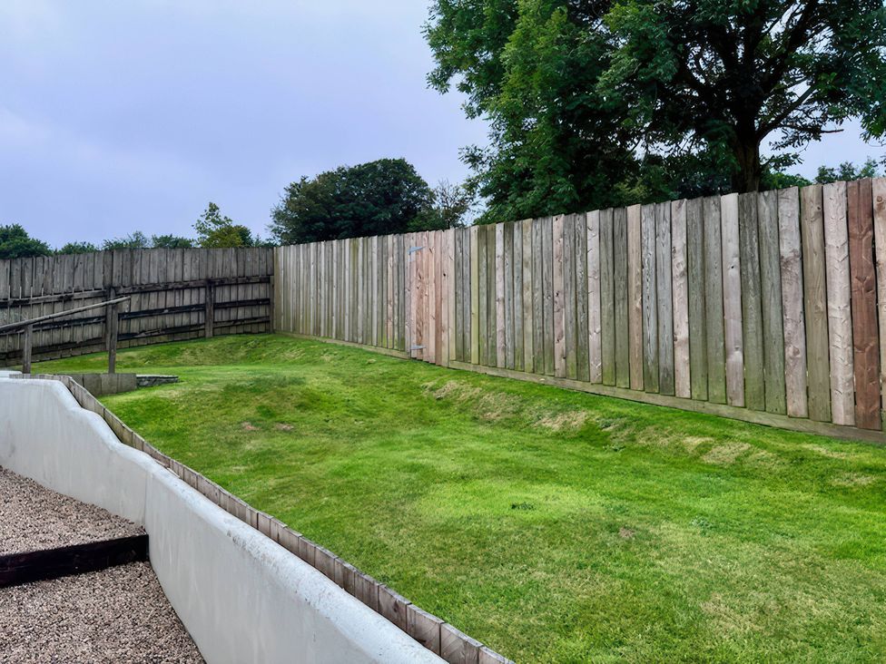 A garden with grass and a wooden fence at Millies Place in Coombe near Grampound