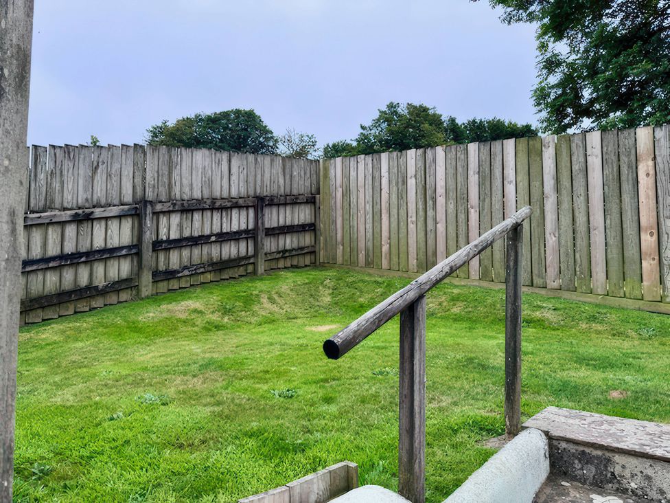 A garden area with a wooden fence and steps at Millies Place in Coombe near Grampound