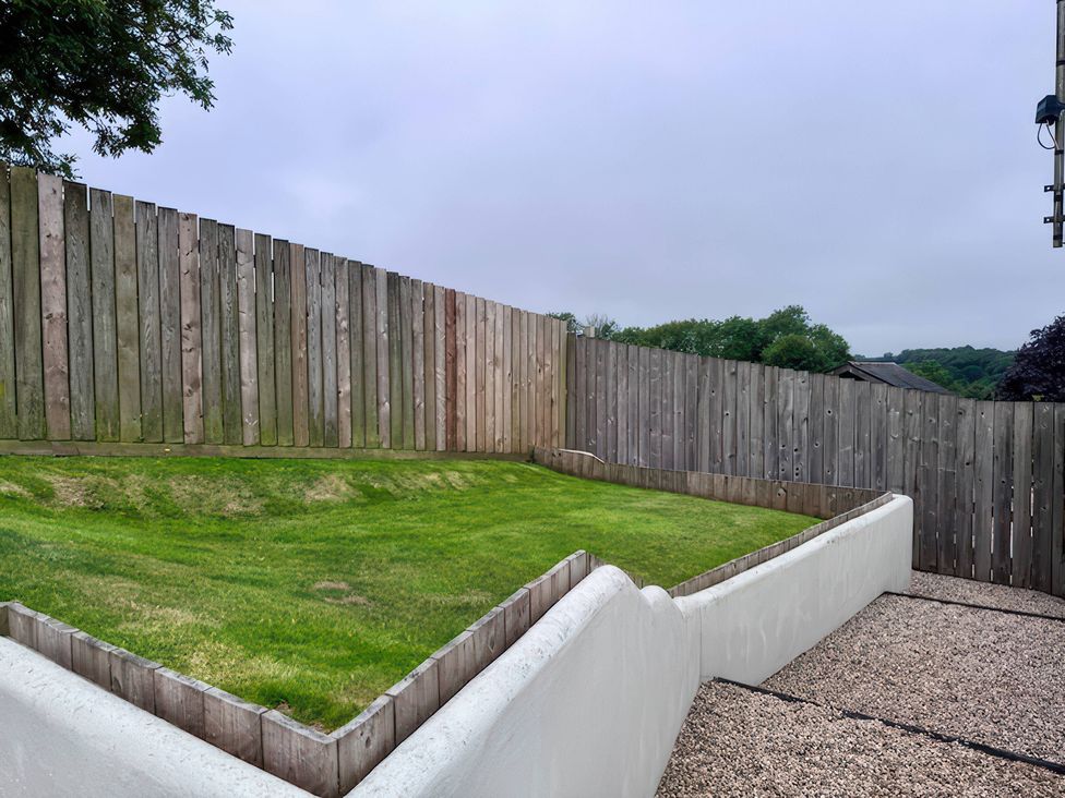 A garden with grass and a wooden fence at Millies Place in Coombe near Grampound