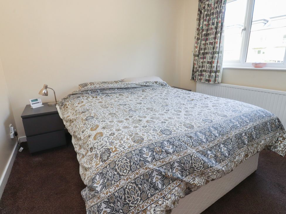 A bedroom with a bed, nightstand, and window at 9 Waterside Fold in Hebden Bridge