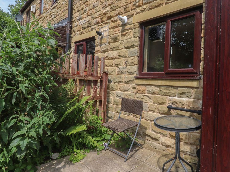 An outdoor area with a chair and table near plants at 9 Waterside Fold in Hebden Bridge