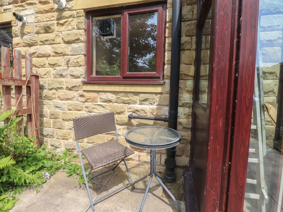 An outdoor seating area with a table and a chair at 9 Waterside Fold Hebden Bridge