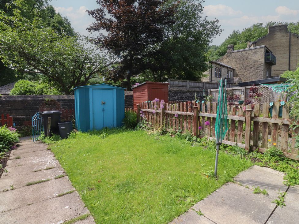 A garden with a blue shed and green grass at 9 Waterside Fold in Hebden Bridge