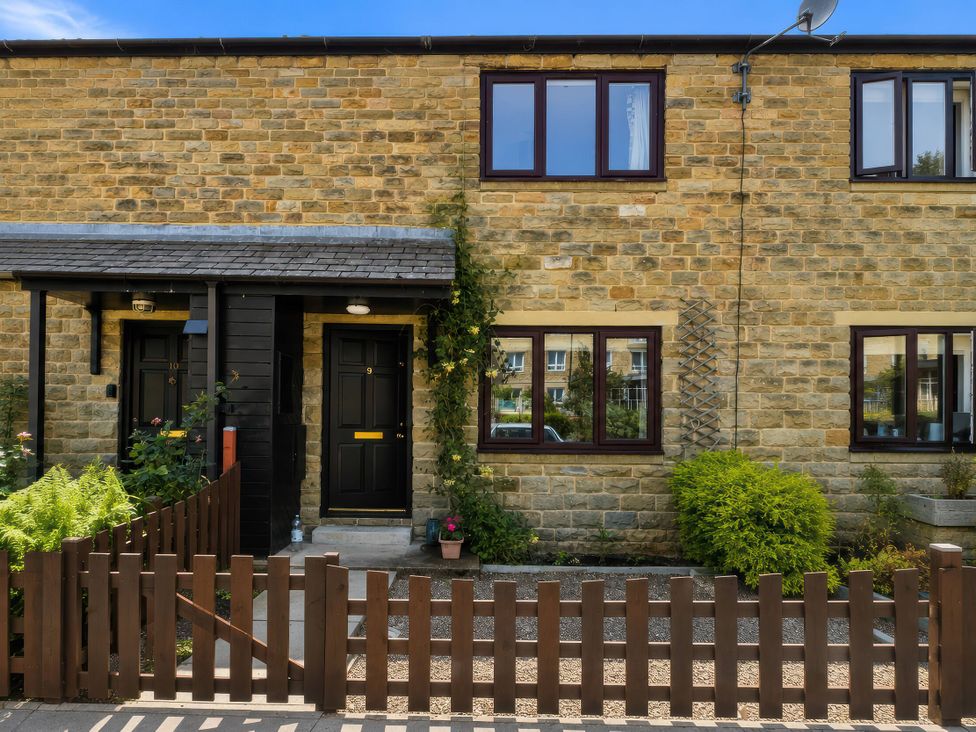 The front of a cottage with stone wall and windows at Beckside Cottage in Hebden Bridge
