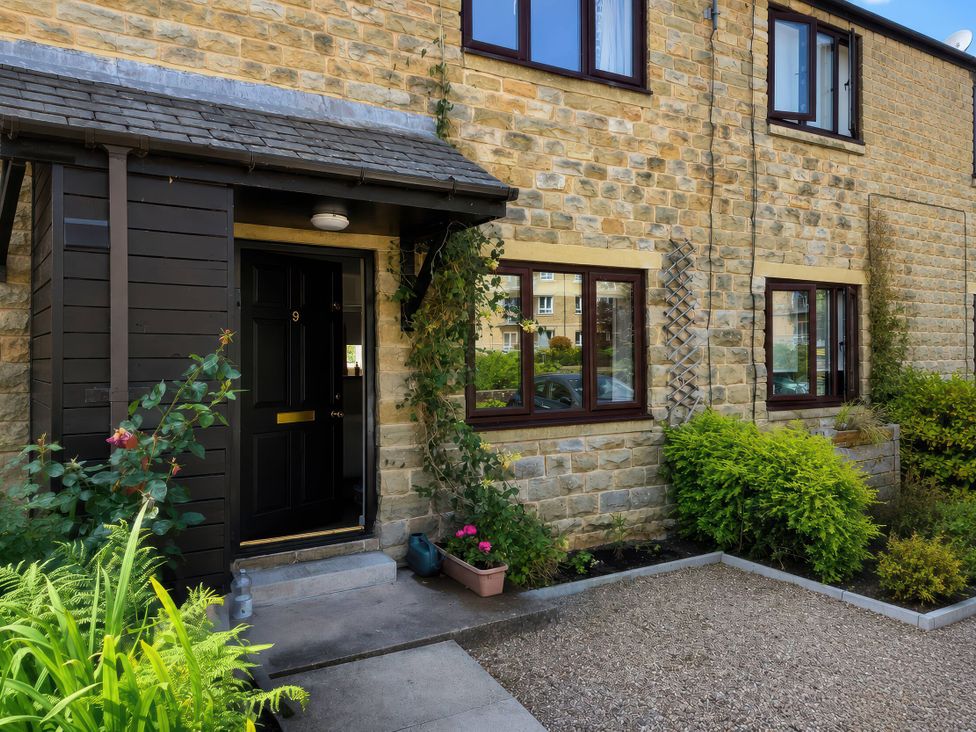 An entrance with a black door and plants at Beckside Cottage in Hebden Bridge