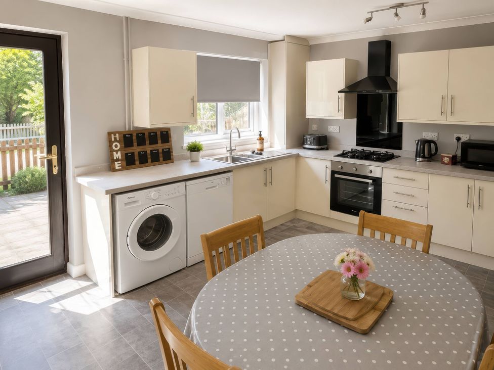 A kitchen with a washing machine and dining table at Beckside Cottage in Hebden Bridge