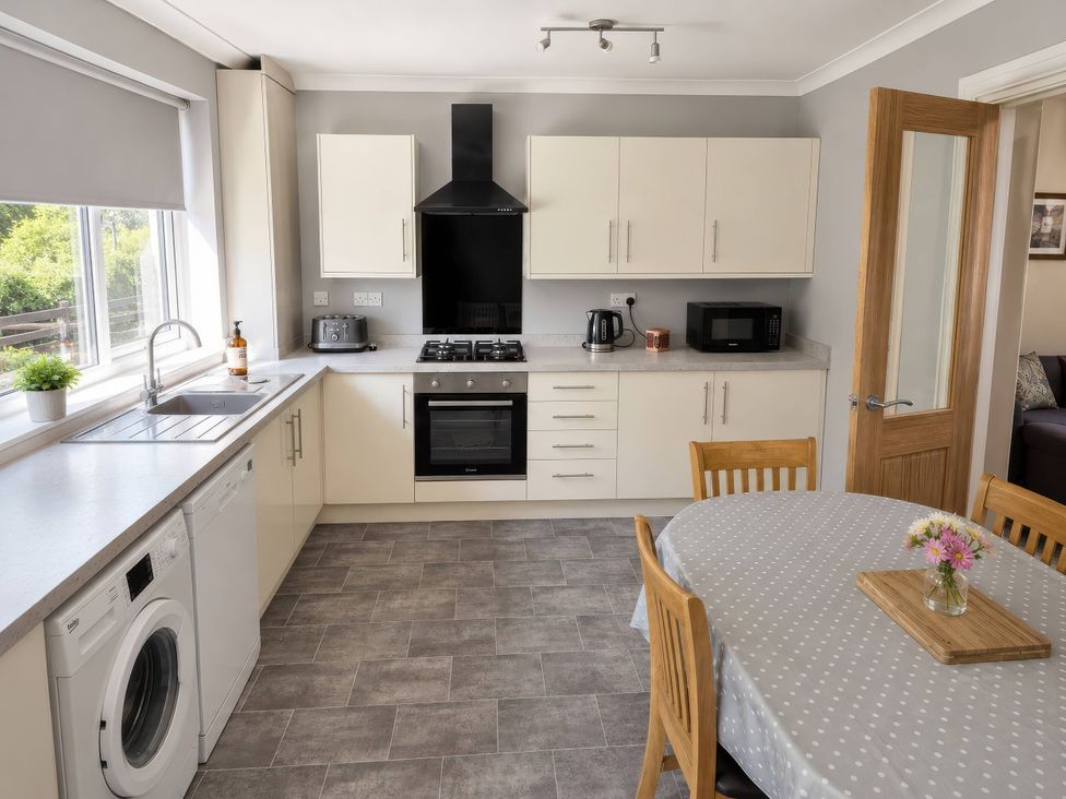 A kitchen with appliances and dining area at Beckside Cottage in Hebden Bridge